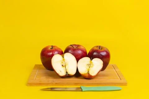 Sliced red apple on a board with knife with yellow background Stock Photos