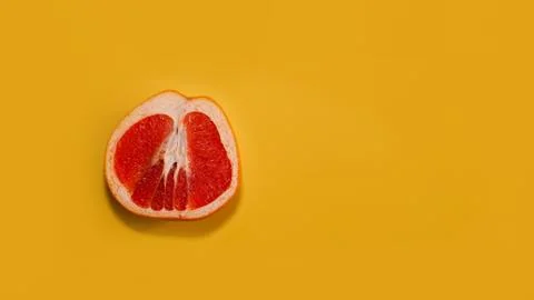 Sliced red grapefruit with copy space on bright yellow background Stock Photos