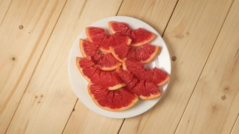 Sliced red grapefruit rotating on a white plate Stock Footage 340526182