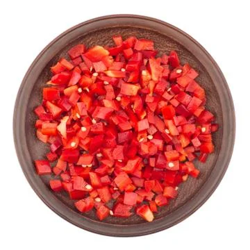 Sliced red pepper in a brown ceramic plate. Isolated on white background. Stock Photos