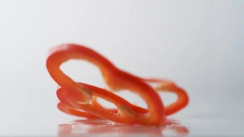 Sliced red pepper falling on water surface. Slow Motion. Stock Footage 79478708