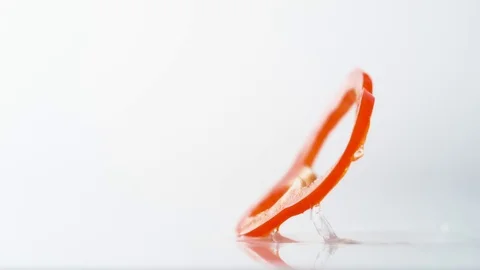A sliced red pepper falling on water surface. Slow Motion. Stock Footage 79511601