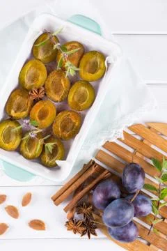 Sliced red plums before baking in a baking dish  with fresh mint, cinnamon, Stock Photos
