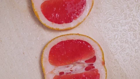 Sliced ripe grapefruit under drops of water rotation close-up Stock Footage 146936055