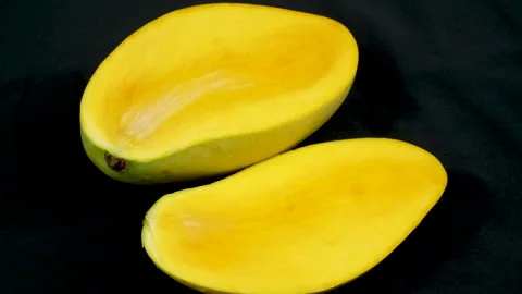 Sliced Ripe Yellow Mango Halves Rotating on Black Background Stock Footage 335259818