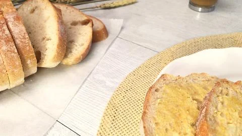 Sliced rustic bread with butter on a white wooden table Stock Photos