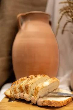 Sliced rustic bread with terracotta jug Фото