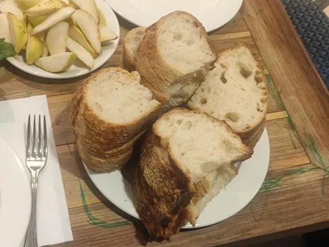 Sliced rustic bread on white plates at a meal table Stock Photos