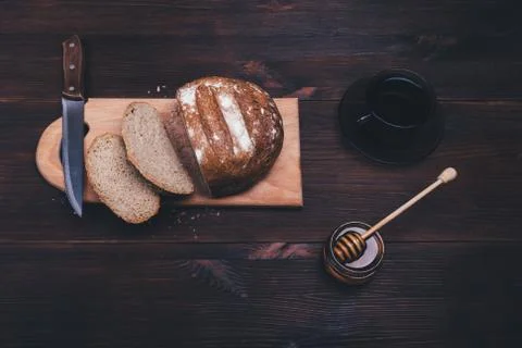 Sliced rye bread on a board next to jar of honey Stock Photos
