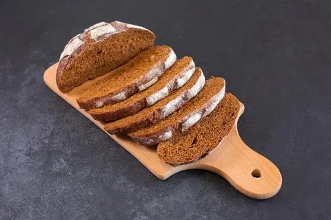 Sliced rye bread on a cuttig Board and a black table. Stock Photos