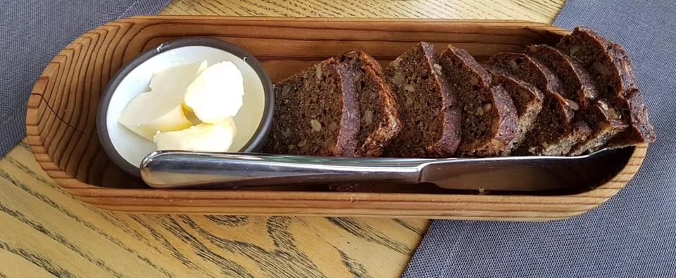 Sliced rye bread with nuts and butter in rosette are served on table in woo.. Stock Photos