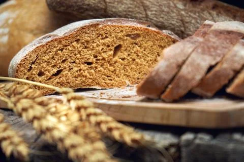 Sliced rye round bread and wheat ears on the old wooden table Foto stock