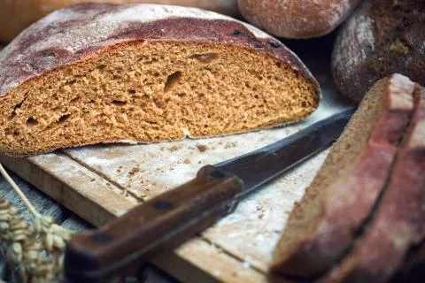Sliced rye round bread and wheat ears witha knife on the old wooden table Foto stock