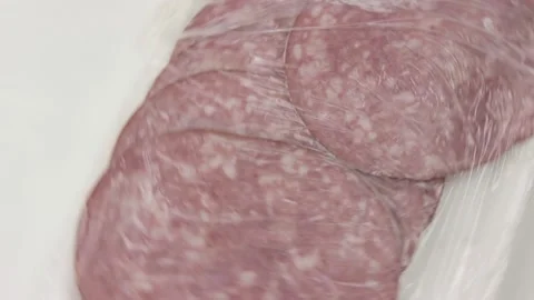 Sliced salami in opened package rotates on a white porcelain dish. Stock Footage 131216286