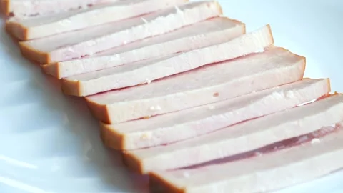 Sliced smoked bacon appetizer rotating on a white plate Vídeo Stock 337892954