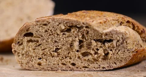 A sliced soft loaf of rye bread lies on the table on a cutting board, a small Stock Footage 318946811