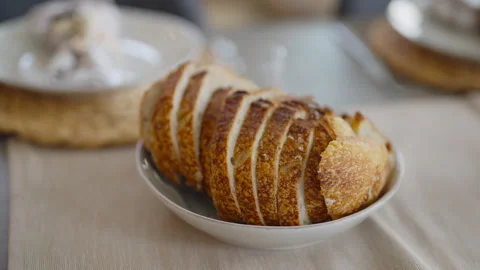 Sliced sourdough bread sitting in a white bowl on a table runner. Stock Footage 278018271