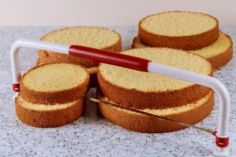 Sliced sponge cake with leveler on table for making wedding cake. Stock Photos