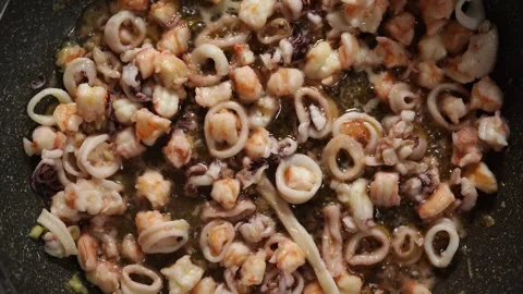 Sliced squid tentacles are fried in oil in a frying pan Stock Footage 266908838