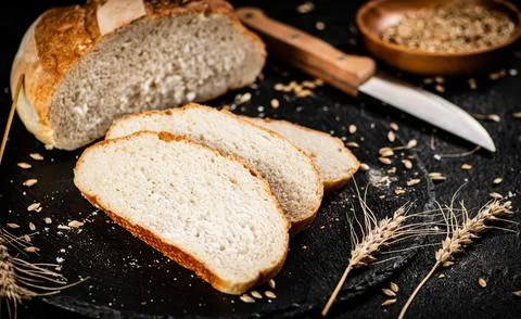 Sliced on a stone board wheat bread with grains. Stock Photos