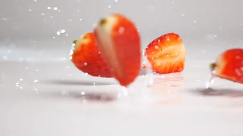 Sliced strawberries fall down on white surface Stock Footage 63082480