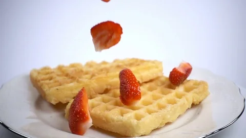Sliced strawberries fall on waffles Stock Footage 74772778
