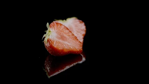 A sliced strawberry rotating on a black background 動画素材 128692435