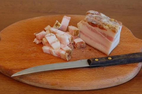 Sliced tasty bacon of salty pork on a chopping board with a knife Stock Photos