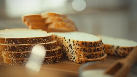 Sliced toast bread topped with sesame seeds rests on a kitchen cutting board Stock Footage 333502091