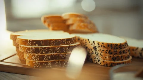 Sliced toast bread topped with sesame seeds rests on a kitchen cutting board Stock Footage 336570765