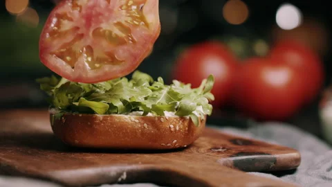 Sliced Tomato Being Placed On A  Bun With Lettuce Video stock 134402373