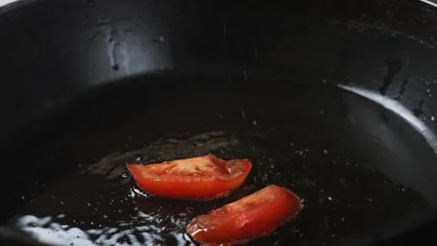 Sliced tomatoes fall into a frying pan with boiling oil. Medium plan. Stock Footage 276504932