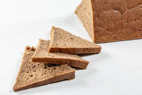 Sliced triangular pieces of black bread on a white table Stock Photos