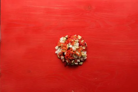 Sliced ​​vegetables are collected in the middle on a red background. Stock Photos