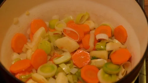 Sliced vegetables being spooned out of a casserole dish Stock Footage 121449658