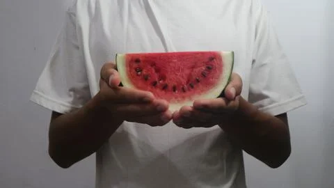 Sliced watermelon in hand isolated white. Red, white, green, and black color. Foto stock
