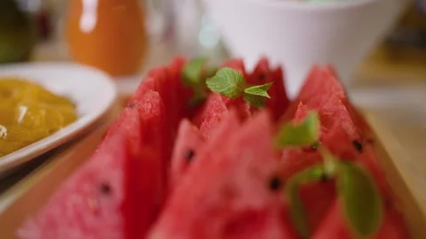 Sliced watermelon triangles with mint garnish on white plate Stock Footage 341166160