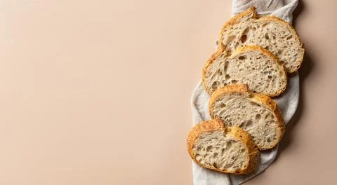 Sliced wheat rustic bread on a linen towel. Artisan bread cut into slices, wide Stock Photos