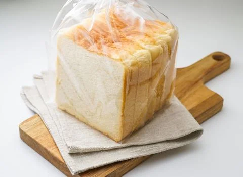 Sliced White Bread Loaf in a Bag on a Wooden Cutting Board side view of bak.. Stock Photos