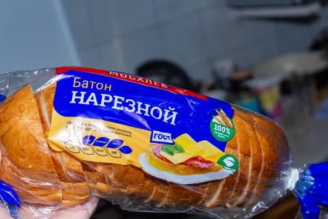 Sliced white bread loaf in plastic packaging with blue label on kitchen Stock Photos
