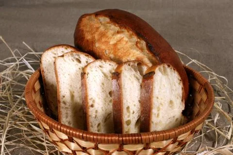 Sliced white bread is in a straw basket on the tablecloth gray linen Stock Photos