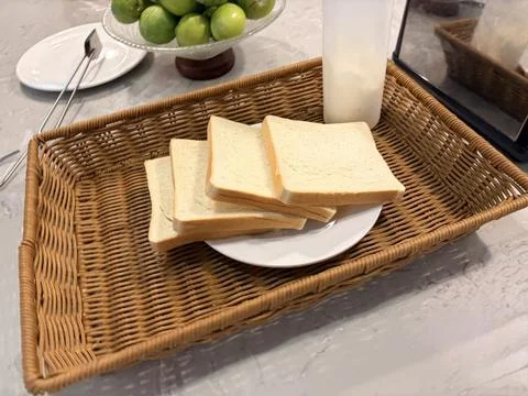 Sliced white bread on a white plate in a wicker basket. Stock Photos