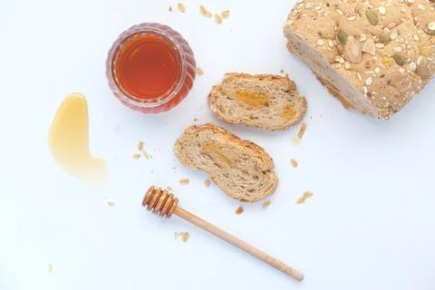 Sliced whole grain bread with oat flakes and honey on white Stock Photos
