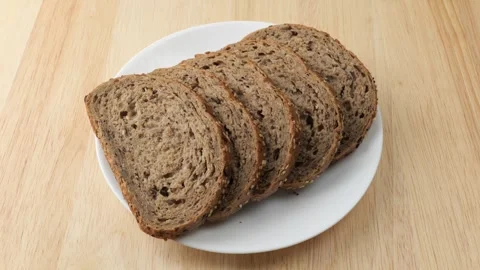 Sliced whole grain bread rotating on white plate Stock Footage 348307745