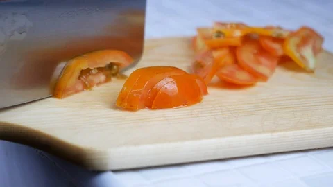 Sliced yellow orange tomatoes with sharp knife on wooden chopping board , pre Stock Footage 89294436