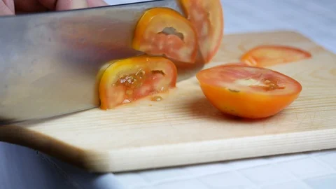 Sliced yellow orange tomatoes with sharp knife on wooden chopping board , pre Stock Footage 89294834