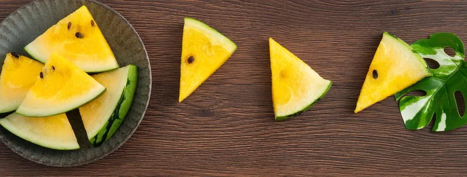 Sliced yellow watermelon pattern flat lay on wooden table background. Stock Photos