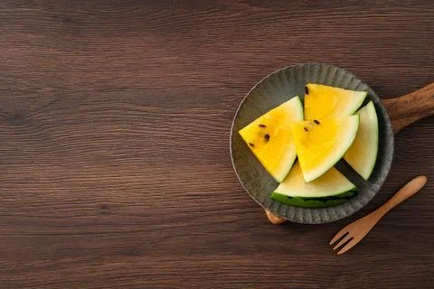 Sliced yellow watermelon pattern flat lay on wooden table background. Stock Photos