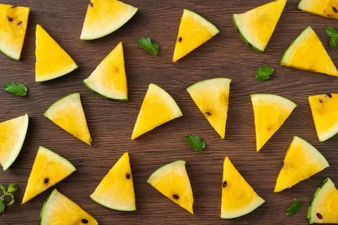 Sliced yellow watermelon pattern flat lay on wooden table background. Stock Photos