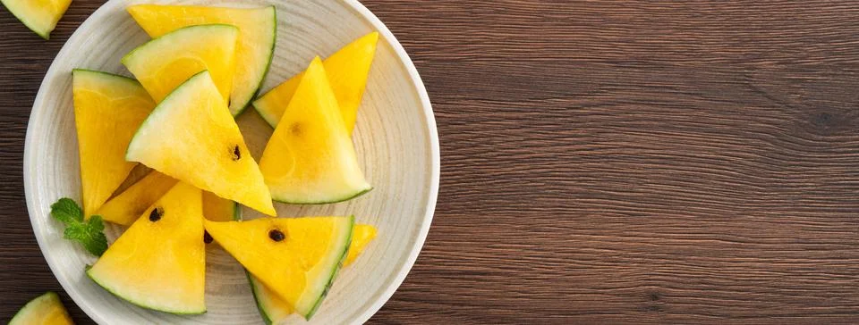 Sliced yellow watermelon pattern flat lay on wooden table background. Stock Photos